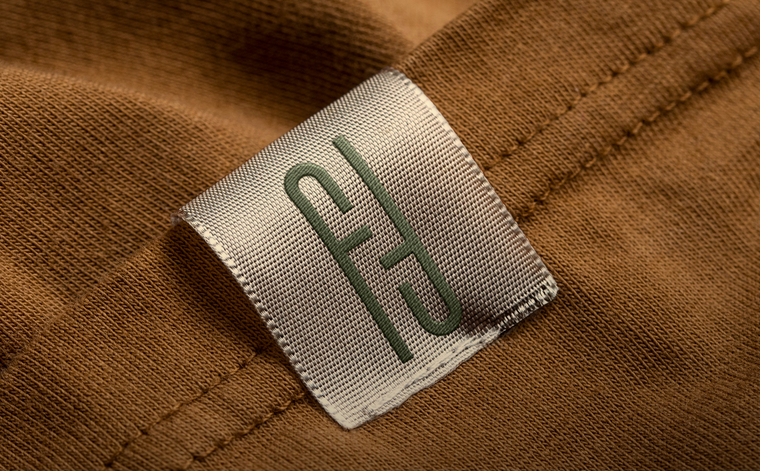 Close-up of a label on brown fabric with a logo.