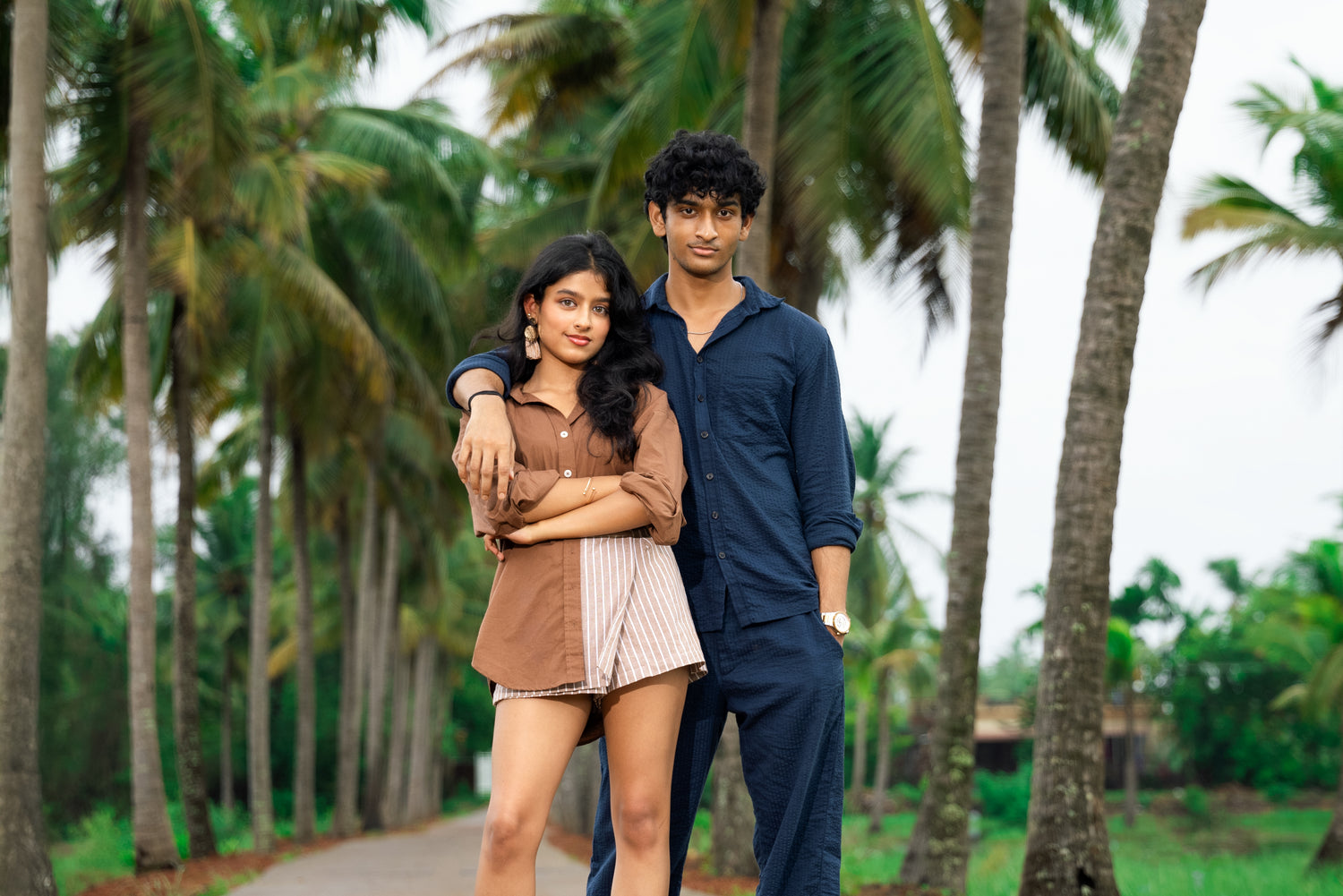 Two people standing together in a tropical setting with palm trees.