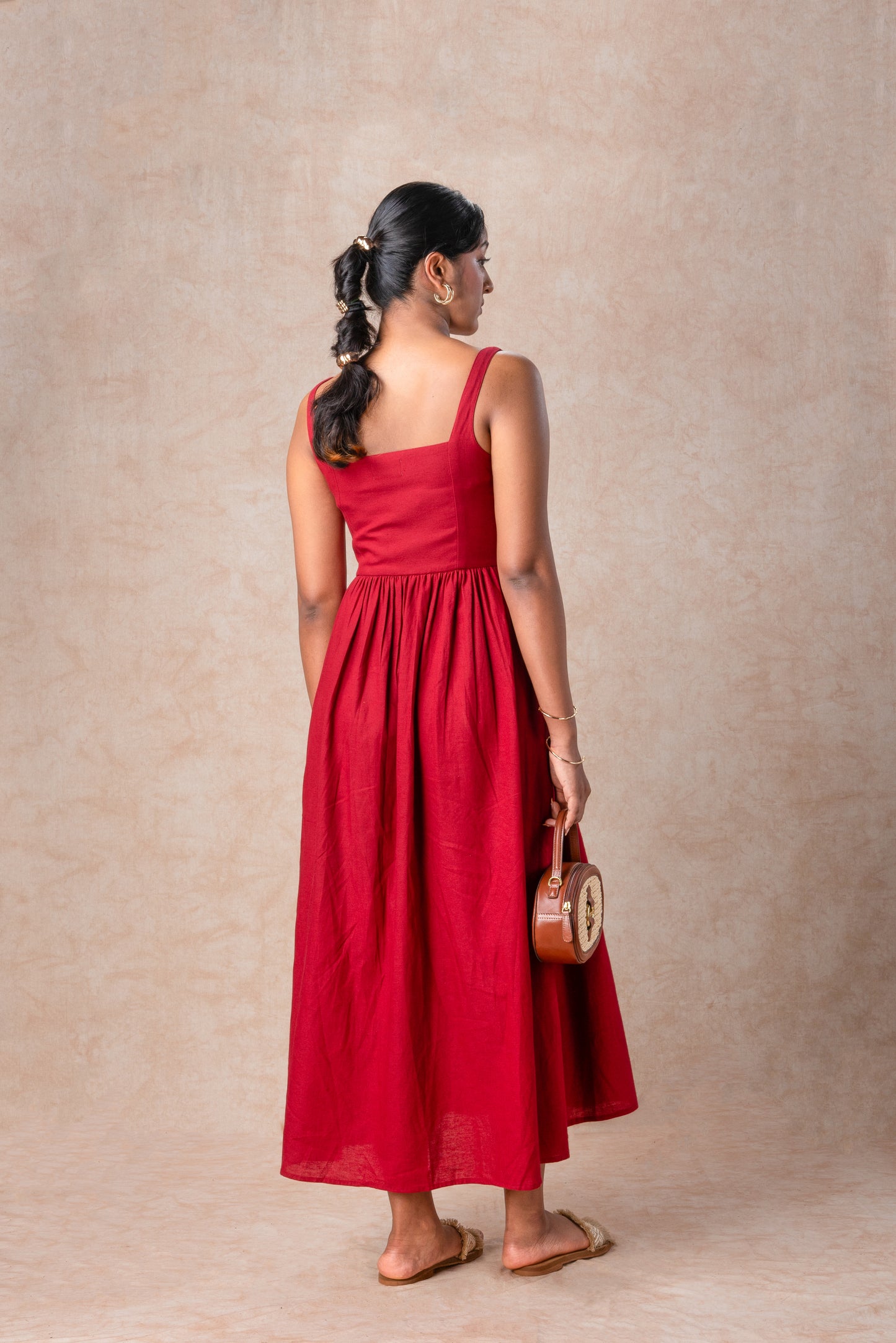 Woman in a red dress standing against a beige background