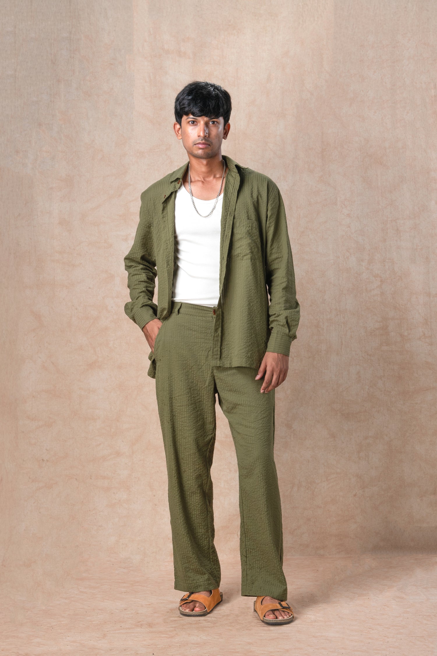 Man wearing a green outfit standing against a beige background