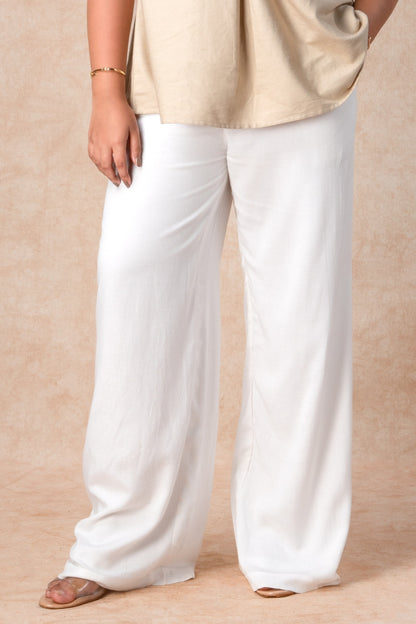 Person wearing a beige top and white pants on a beige background
