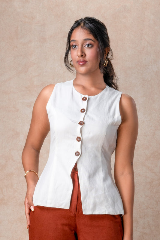Woman wearing a white sleeveless top with brown buttons against a beige background